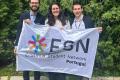 Rita, Vinha and Gonçalo stand behind an ESN Portugal flag, smiling.