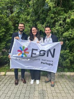 Rita, Vinha and Gonçalo stand behind an ESN Portugal flag, smiling.